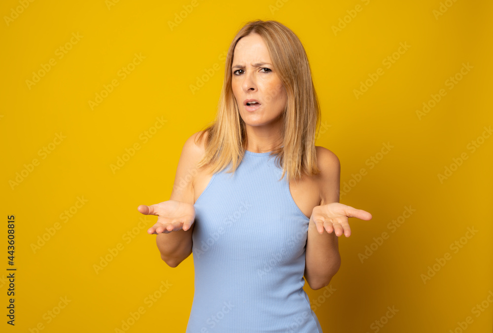 Young woman over isolated yellow background making doubts gesture. Young woman over isolated yellow background making doubts gesture.