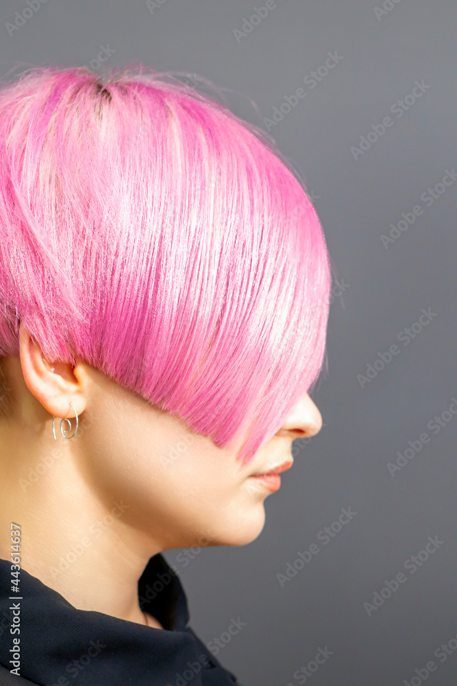 Profile portrait of a young caucasian woman with pink bob haircut isolated on a gray background. Profile portrait of a young caucasian woman with pink bob haircut isolated on a gray background.