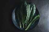 Cavolo nero black curly kale vegetable on black plate