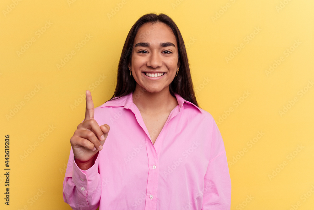 Young mixed race woman isolated on yellow background showing number one with finger. Young mixed race woman isolated on yellow background showing number one with finger.