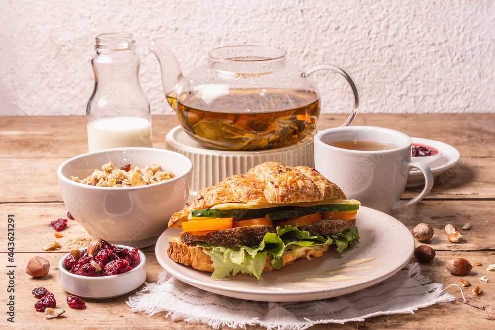 Healthy breakfast concept. Morning good mood with tea, croissant, granola, milk, and jam Healthy breakfast concept. Morning good mood with tea, croissant, granola, milk, and jam