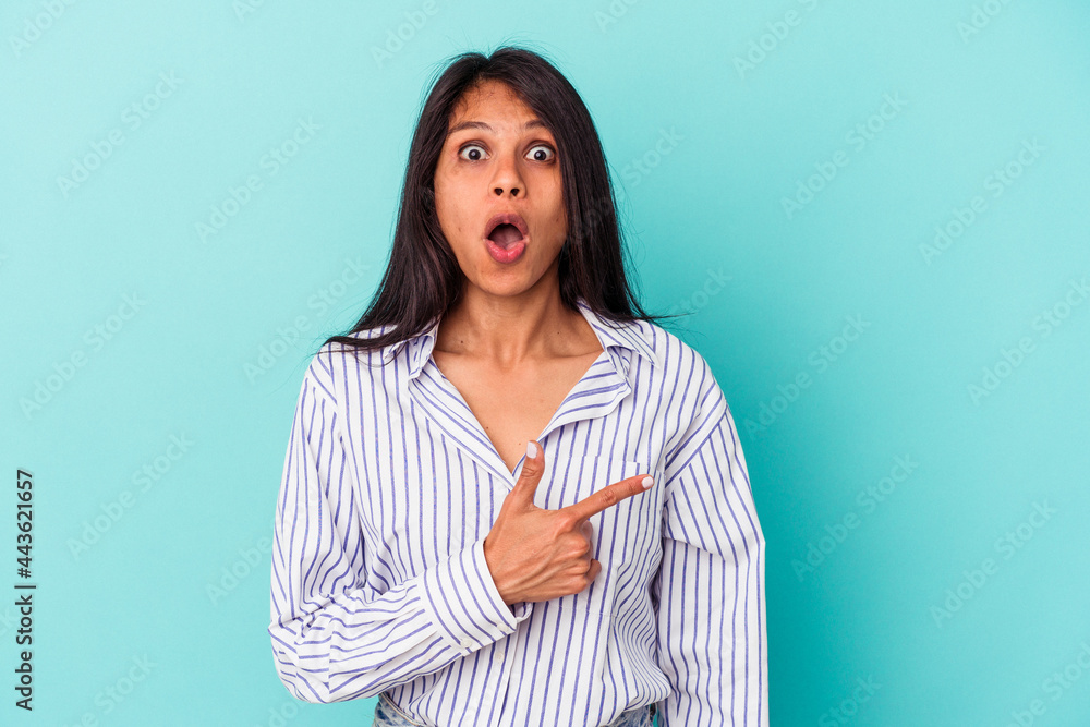 Obraz premium Young latin woman isolated on blue background pointing to the side