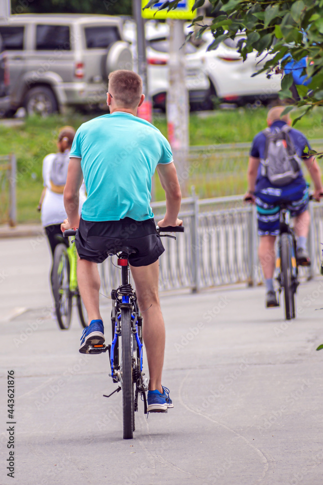 A young man rides on a bike path on a summer day
