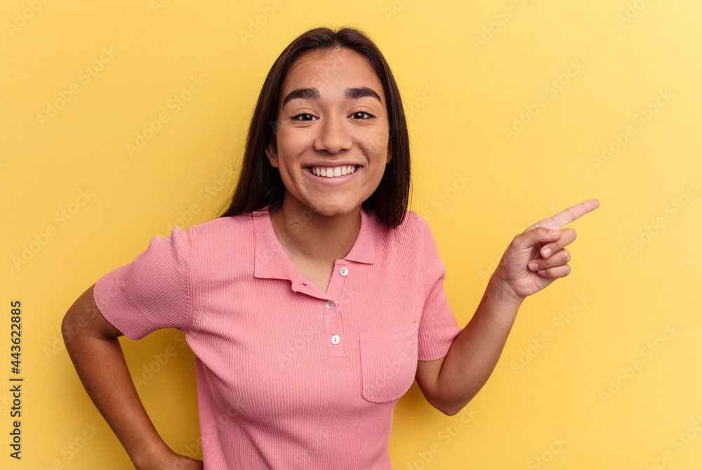 Young mixed race woman isolated on yellow background smiling cheerfully pointing with forefinger away. Young mixed race woman isolated on yellow background smiling cheerfully pointing with forefinger away.