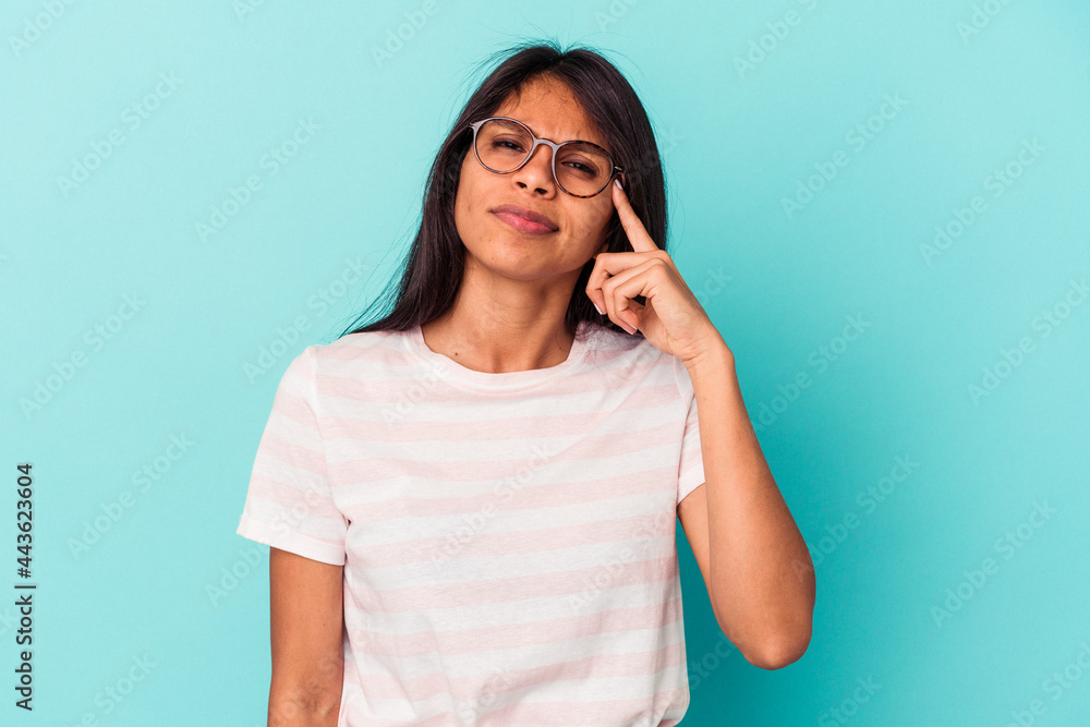 Young latin woman isolated on blue background pointing temple with finger, thinking, focused on a task. Young latin woman isolated on blue background pointing temple with finger, thinking, focused on a task.