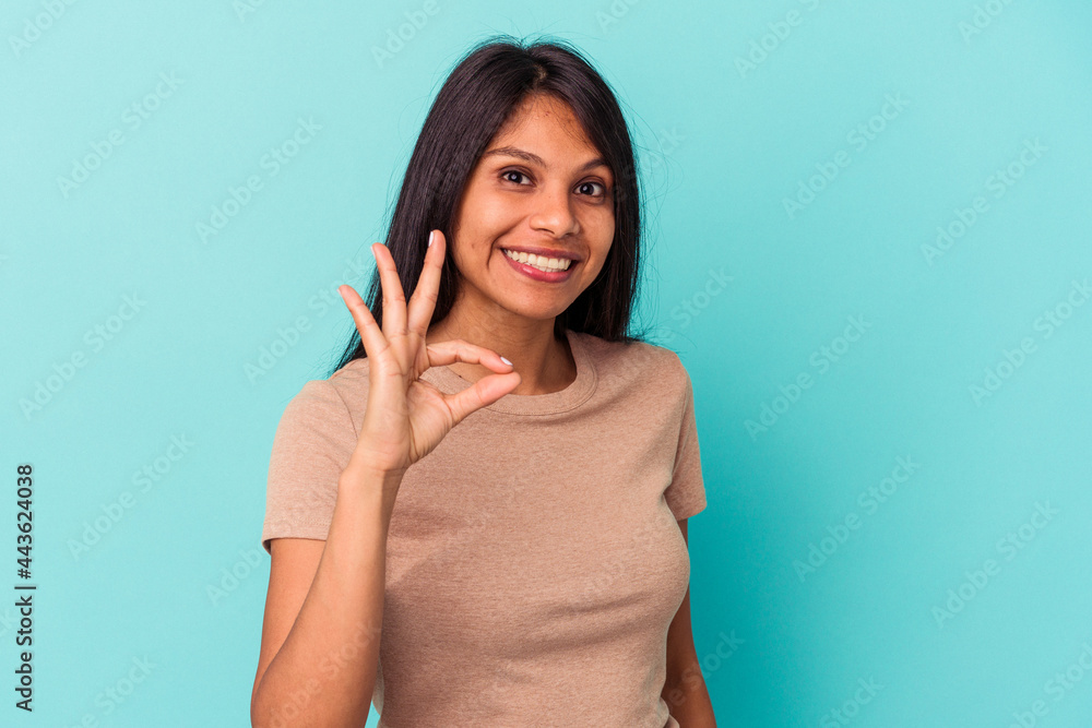 Young latin woman isolated on blue background cheerful and confident showing ok gesture. Young latin woman isolated on blue background cheerful and confident showing ok gesture.