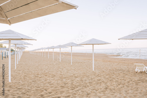 Empty sandy beach alond the sea with white umbrellas. Beach without tourists due to pandemic photo