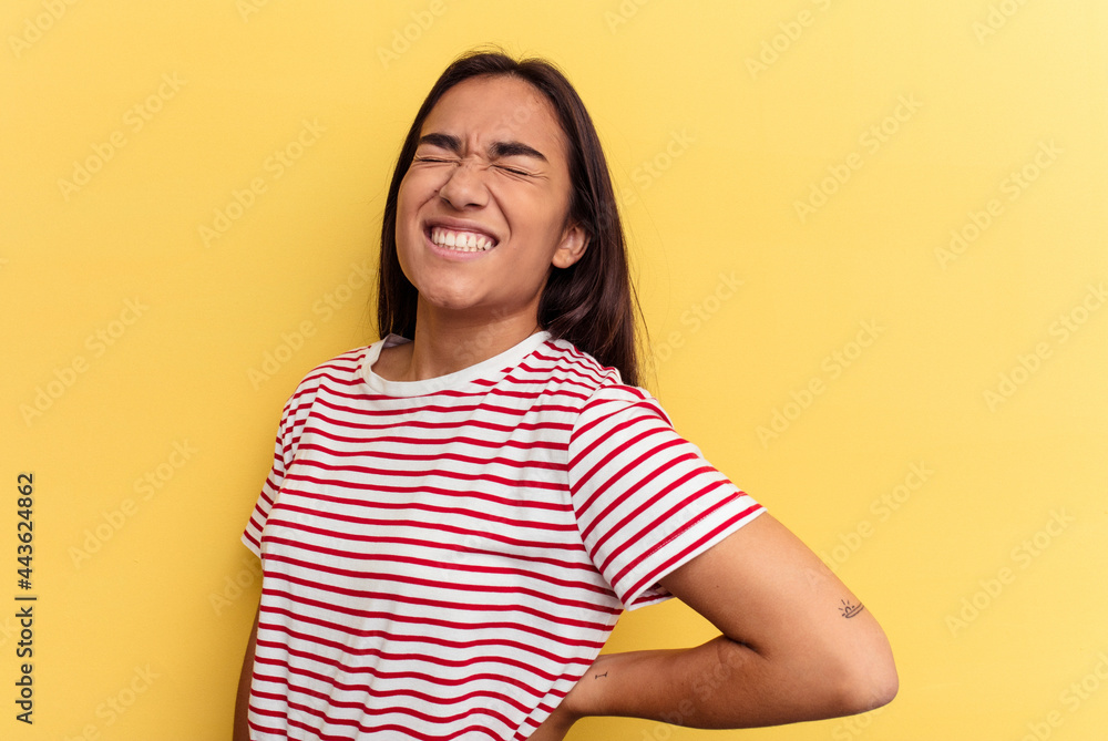 Young mixed race woman isolated on yellow background suffering a back pain. Young mixed race woman isolated on yellow background suffering a back pain.