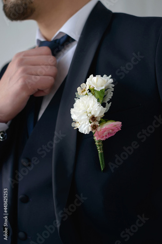 Wallpaper Mural Groom in a dark blue suit with a boutonniere adjusts his tie looking to the side in close-up Torontodigital.ca