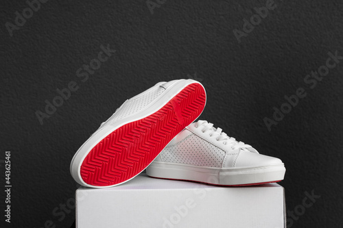 White sneakers with red sole on the box at black background photo