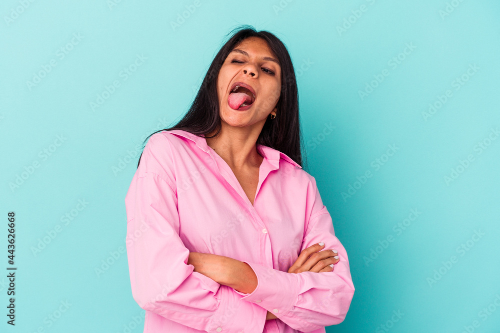 Young latin woman isolated on blue background funny and friendly sticking out tongue. Young latin woman isolated on blue background funny and friendly sticking out tongue.