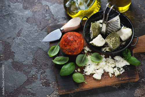 Swiss belper knolle cheese with green basil leaves and olive oil, horizontal shot on a brown stone background with space photo