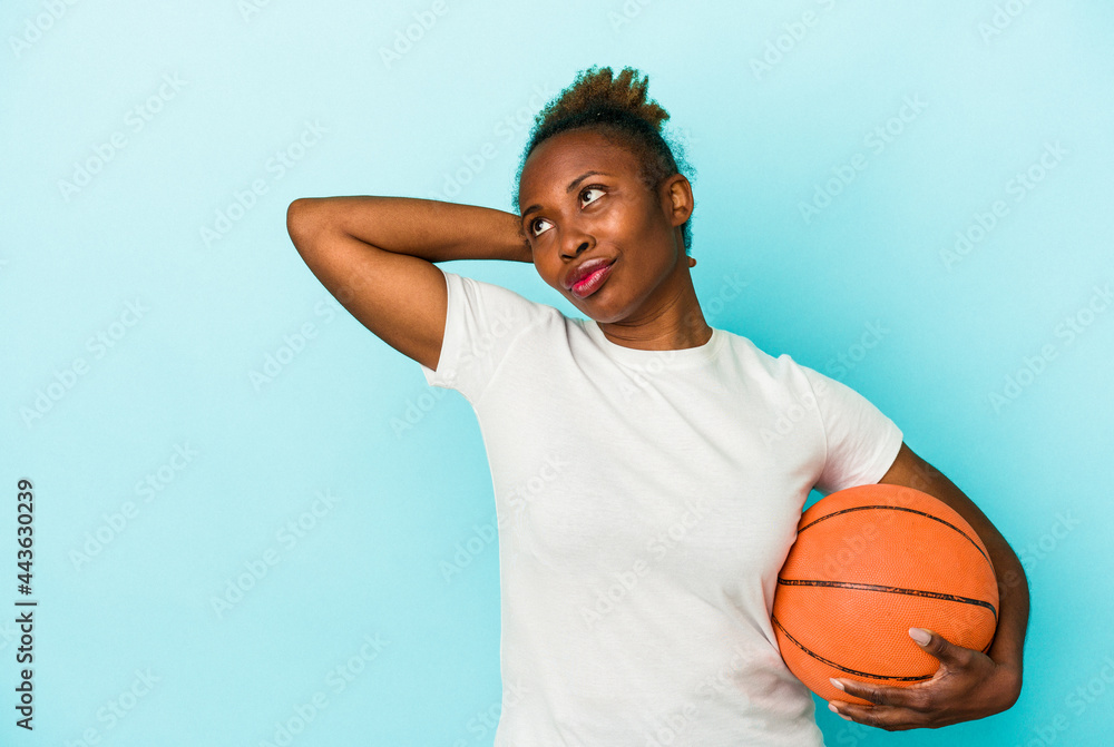 Young african american woman playing basketball isolated on blue background touching back of head, thinking and making a choice.