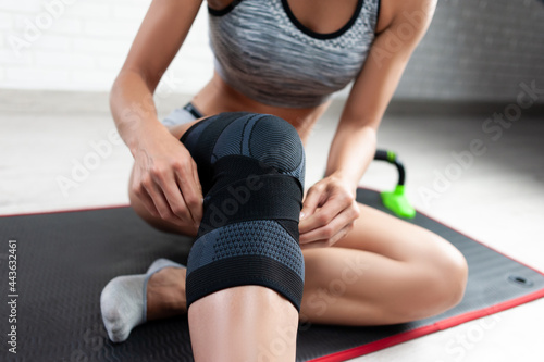 Foto a sporty woman in a fixing knee pad for sports trains at home restores the knee
