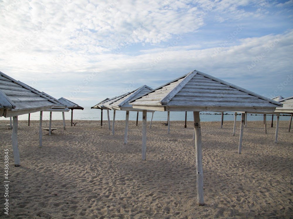 Clean, flat beach by the sea with wooden mushrooms from the sun Clean, flat beach by the sea with wooden mushrooms from the sun