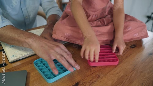 A man and a child are playing Poppit. A man and a girl compete by clicking on Poppit bubbles An anti-stress toy Popular trends of 2021 Self-isolation The family plays Poppit in the office on a break