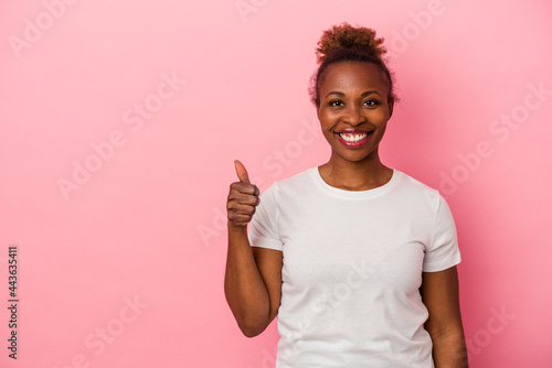 Young african american woman isolated on pink background smiling and raising thumb up