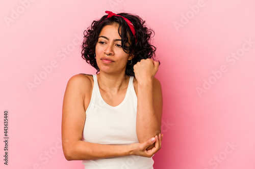 Young curly latin woman isolated on pink background confused, feels doubtful and unsure.