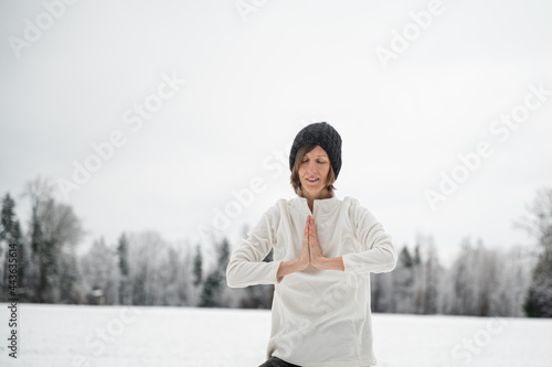 Peaceful young woman meditating outside in snowy nature