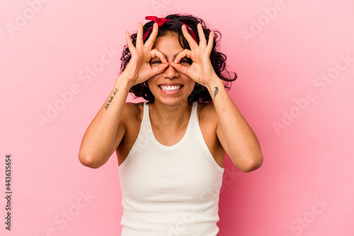 Young curly latin woman isolated on pink background excited keeping ok gesture on eye.