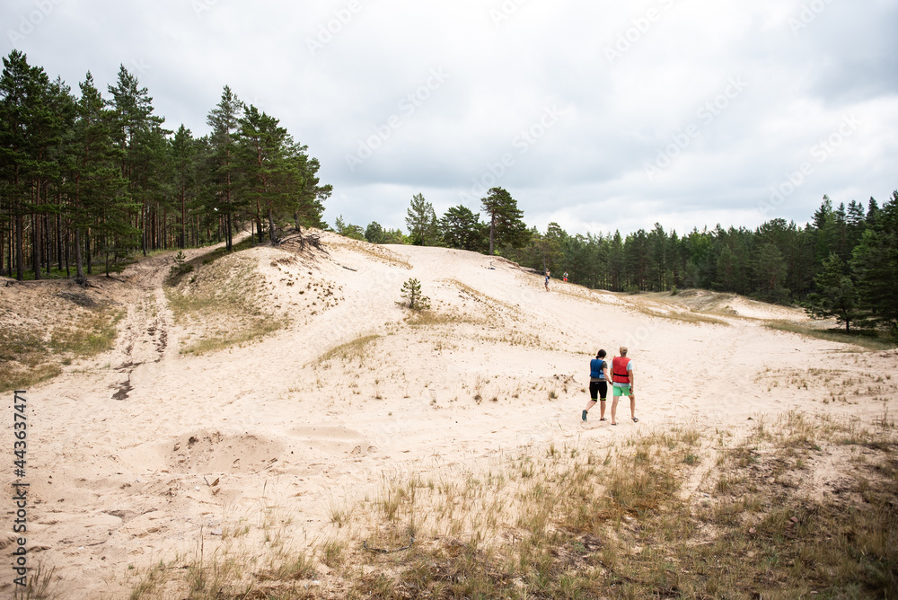 People walk along the dunes in Irbene, Latvia.