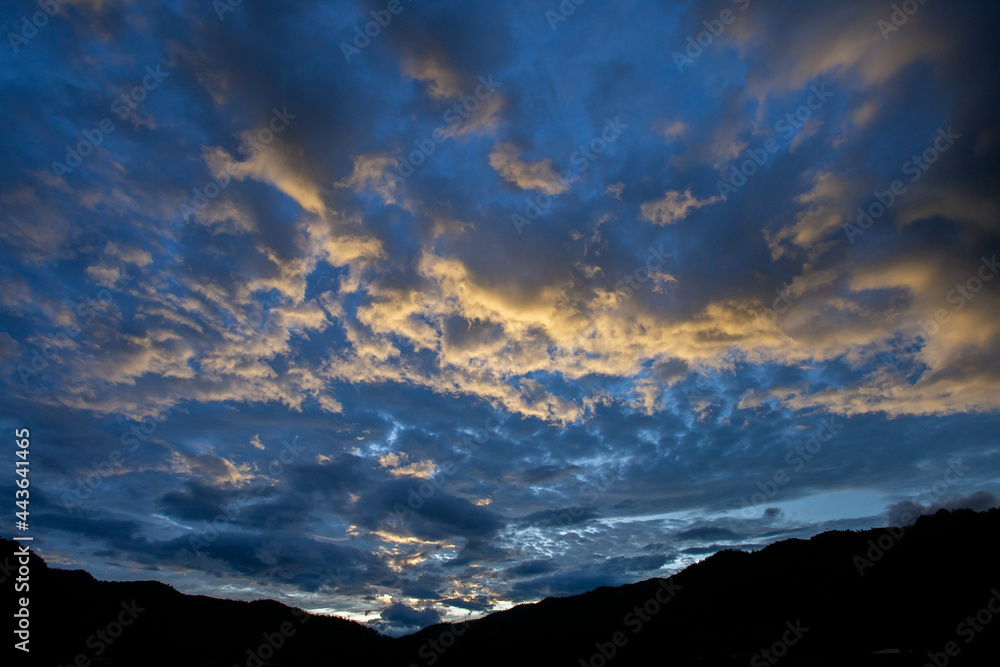 mountain scenery silhouette blue sky Yellow-orange clouds after sunset and after rain, evening. Beautiful evening sky image for the blue background. mountain scenery silhouette blue sky Yellow-orange clouds after sunset and after rain, evening. Beautiful evening sky image for the blue background.