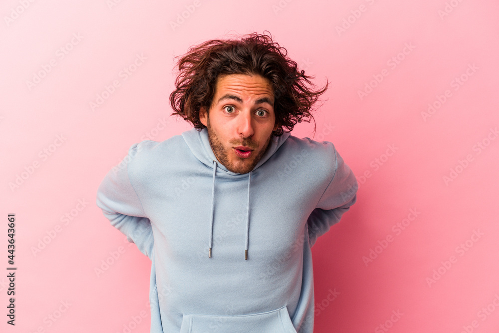 Young caucasian man isolated on pink bakcground being shocked because of something she has seen.