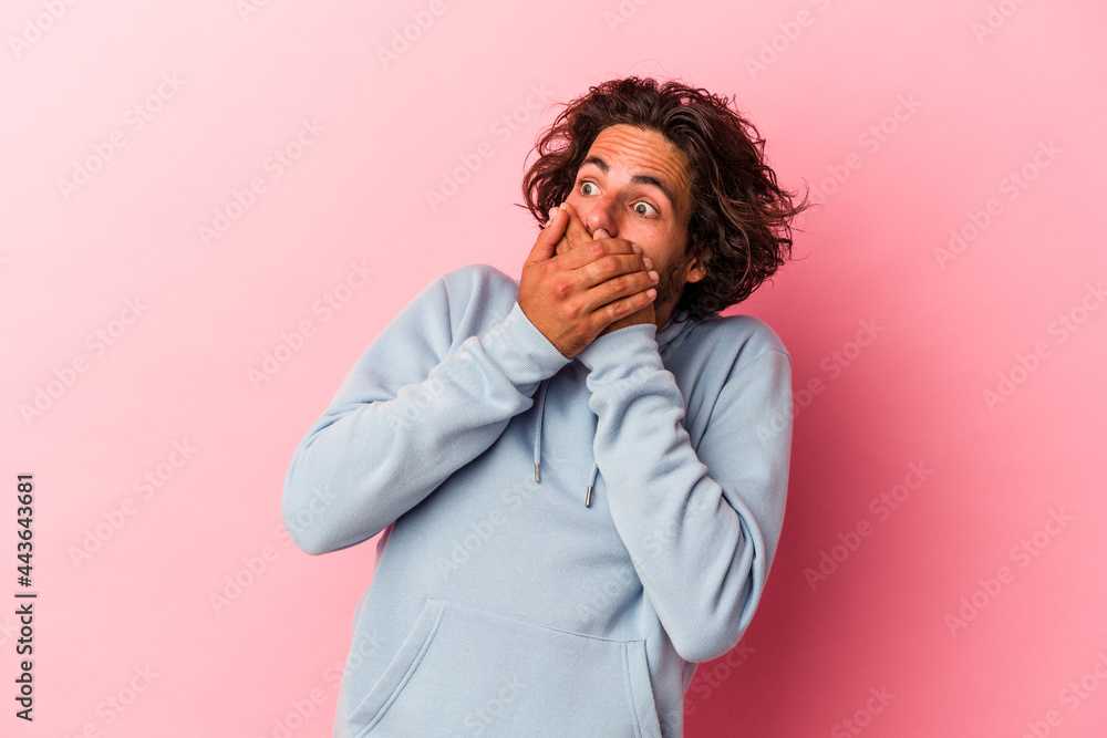 Young caucasian man isolated on pink bakcground thoughtful looking to a copy space covering mouth with hand. Young caucasian man isolated on pink bakcground thoughtful looking to a copy space covering mouth with hand.