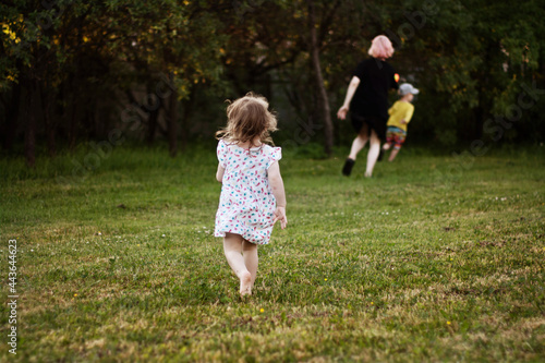children run after each other. a girl and a boy in summer clothes play catch-up in the garden in the summer