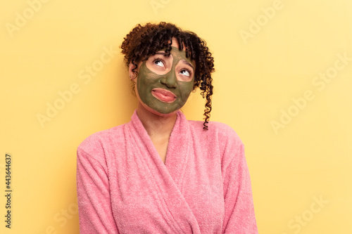Young mixed race wearing facial mask isolated on yellow background dreaming of achieving goals and purposes