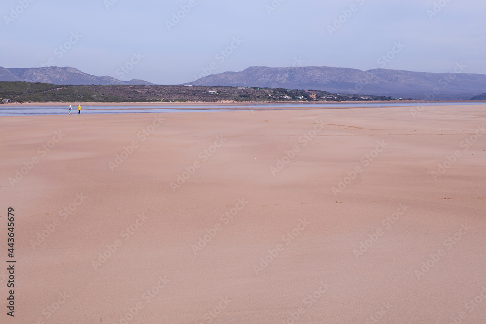 Two people walking on a beach in Witsand, South Africa Two people walking on a beach in Witsand, South Africa