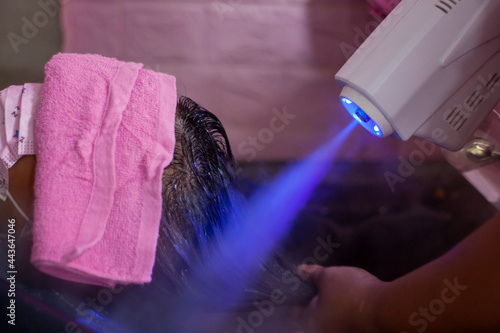 Cuadro en lienzo Asian little girl wearing a mask to prevent the Novel Coronavirus disease starting in 2019 (Covid-19) while let the beautician their hair spa with Nano Spray Gun Blu-​ray Anion at the beauty salon