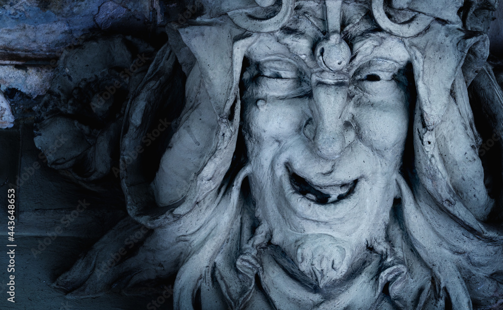 Monster face of aGreek antique god daimon of eager rivalry, envy, jealousy, and zeal Zelus (Zelos). Fragment of an ancient stone statue. Horizontal image. Monster face of aGreek antique god daimon of eager rivalry, envy, jealousy, and zeal Zelus (Zelos). Fragment of an ancient stone statue. Horizontal image.