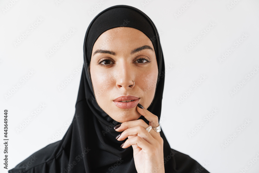 A portrait of a pensive muslim woman with pierced nose holding a hand near the face A portrait of a pensive muslim woman with pierced nose holding a hand near the face