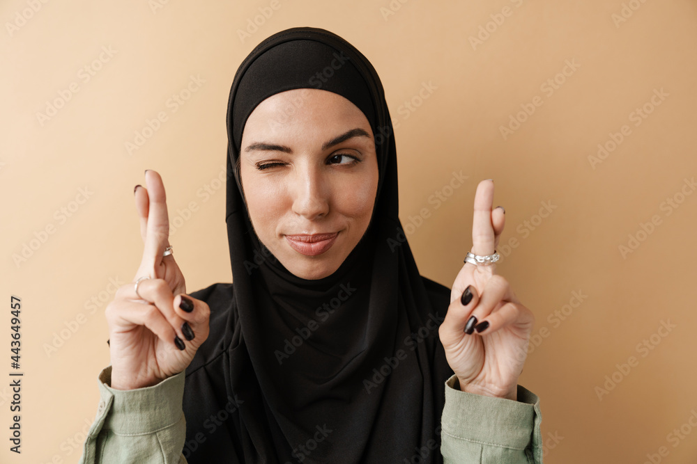 A portrait of the positive muslim woman doing praying gesture and winking with one eye A portrait of the positive muslim woman doing praying gesture and winking with one eye