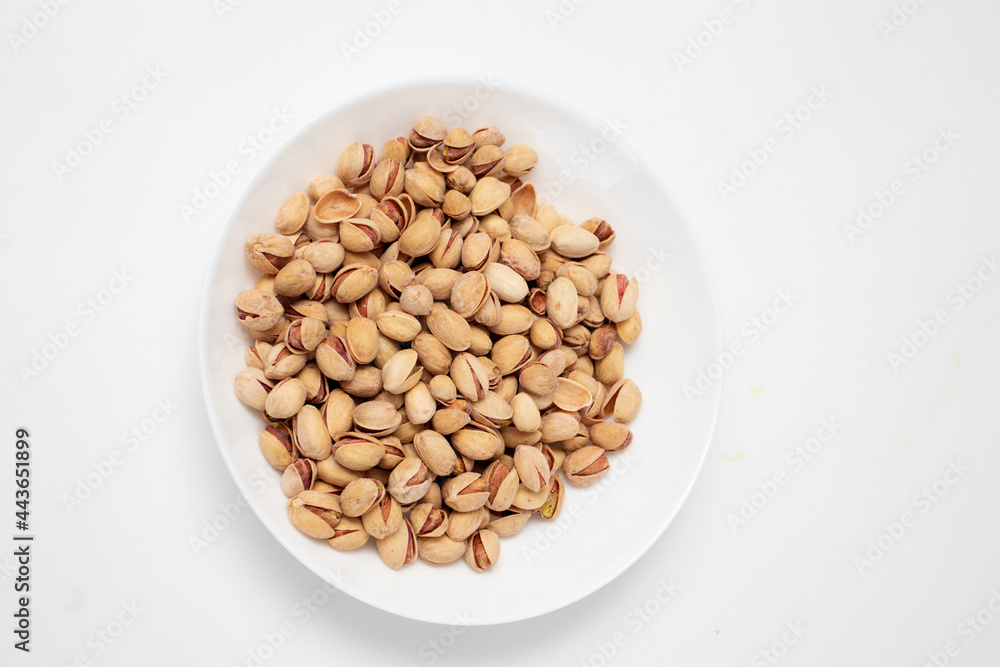 Pistachios nuts in white bowl top view Pistachios nuts in white bowl top view