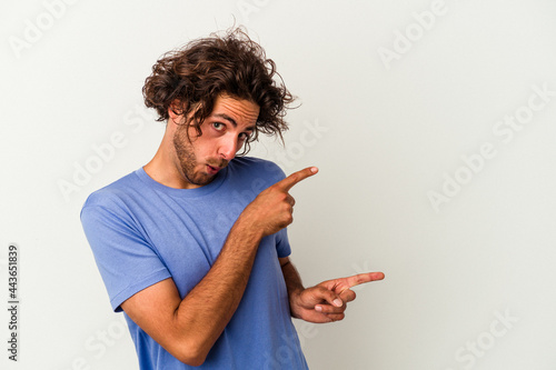 Young caucasian man isolated on white background pointing with forefingers to a copy space, expressing excitement and desire.