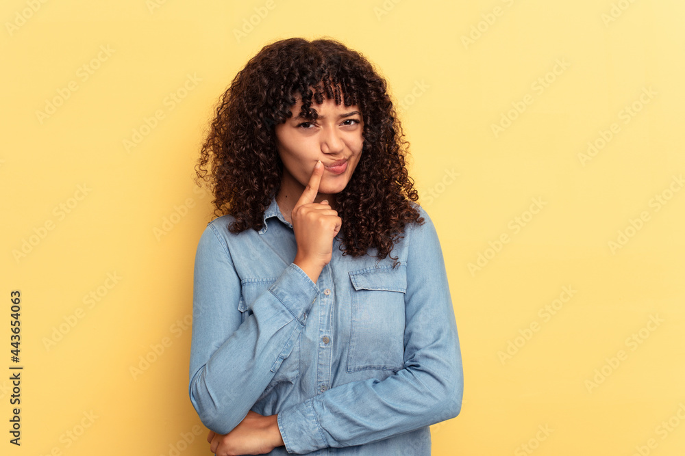 Young mixed race woman isolated on yellow background unhappy looking in camera with sarcastic expression. Young mixed race woman isolated on yellow background unhappy looking in camera with sarcastic expression.