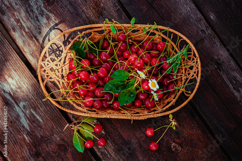 Appetizing cherries in a wicker basket. Ripe cherries on a wooden background.