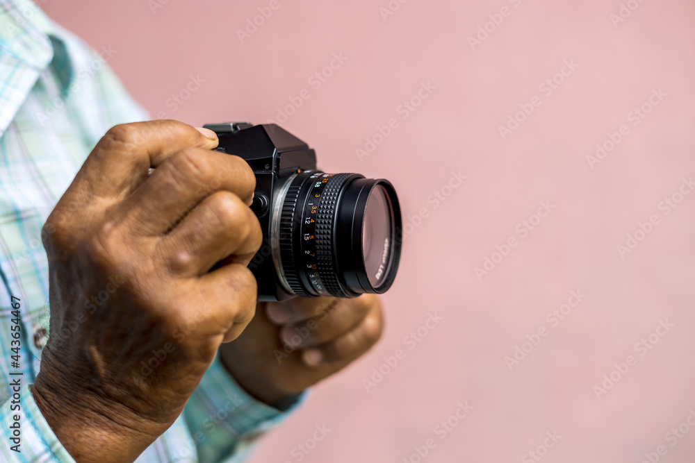 Both hands of an elderly Thai man holding an old film camera.