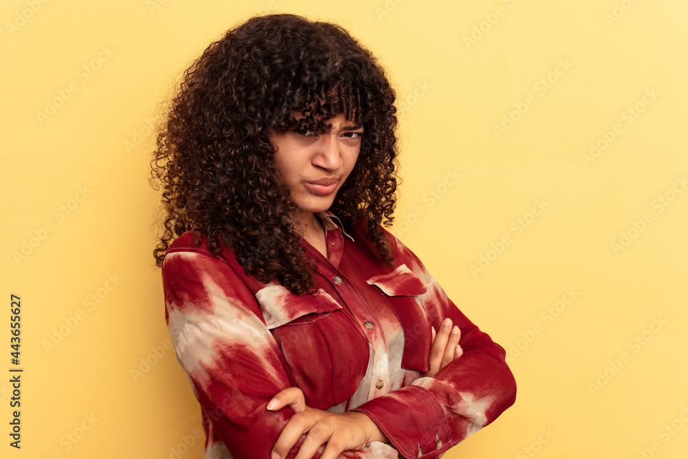 Young mixed race woman isolated on yellow background frowning face in displeasure, keeps arms folded. Young mixed race woman isolated on yellow background frowning face in displeasure, keeps arms folded.