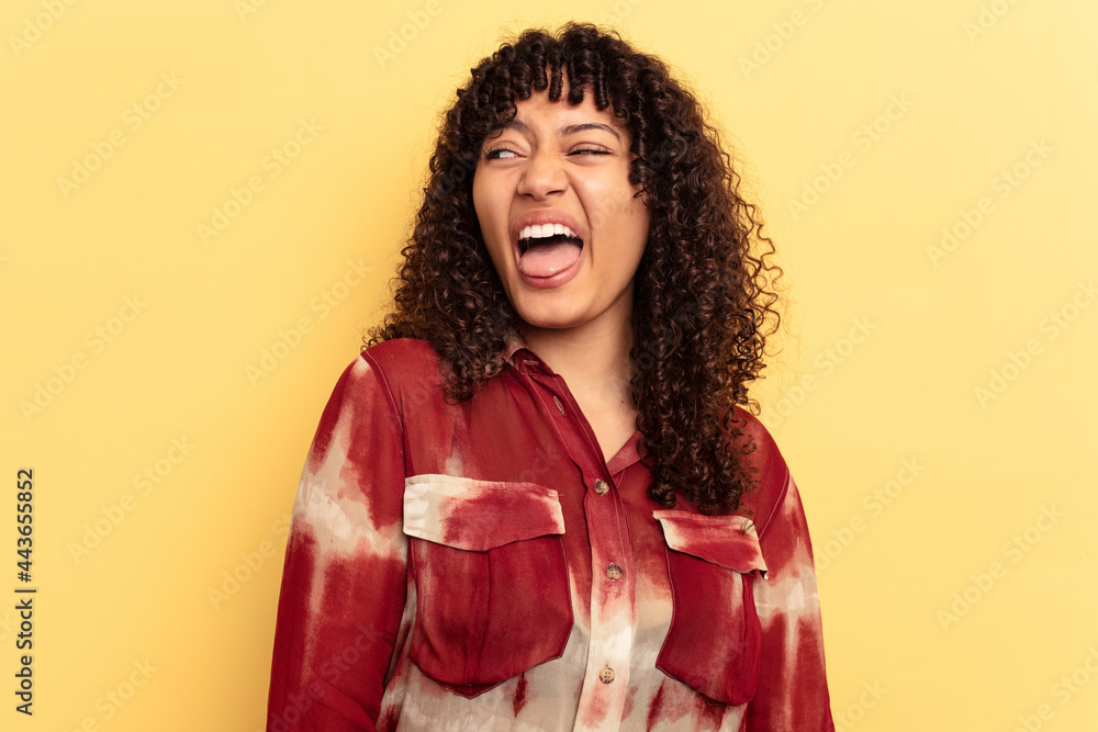 Young mixed race woman isolated on yellow background funny and friendly sticking out tongue. Young mixed race woman isolated on yellow background funny and friendly sticking out tongue.