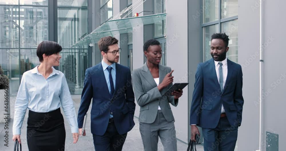 Great job. Positive satisfied young diverse colleagues in suit is walking at the street and discussing something with smile. Business concept Great job. Positive satisfied young diverse colleagues in suit is walking at the street and discussing something with smile. Business concept