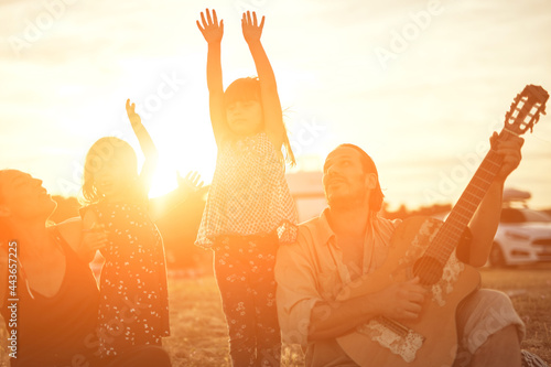 Family on a vacation, singing, playing music on a guitar and enjoying summertime vibes.