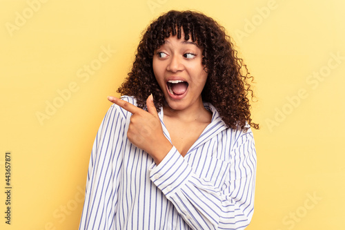 Young mixed race woman isolated on yellow background looks aside smiling, cheerful and pleasant.