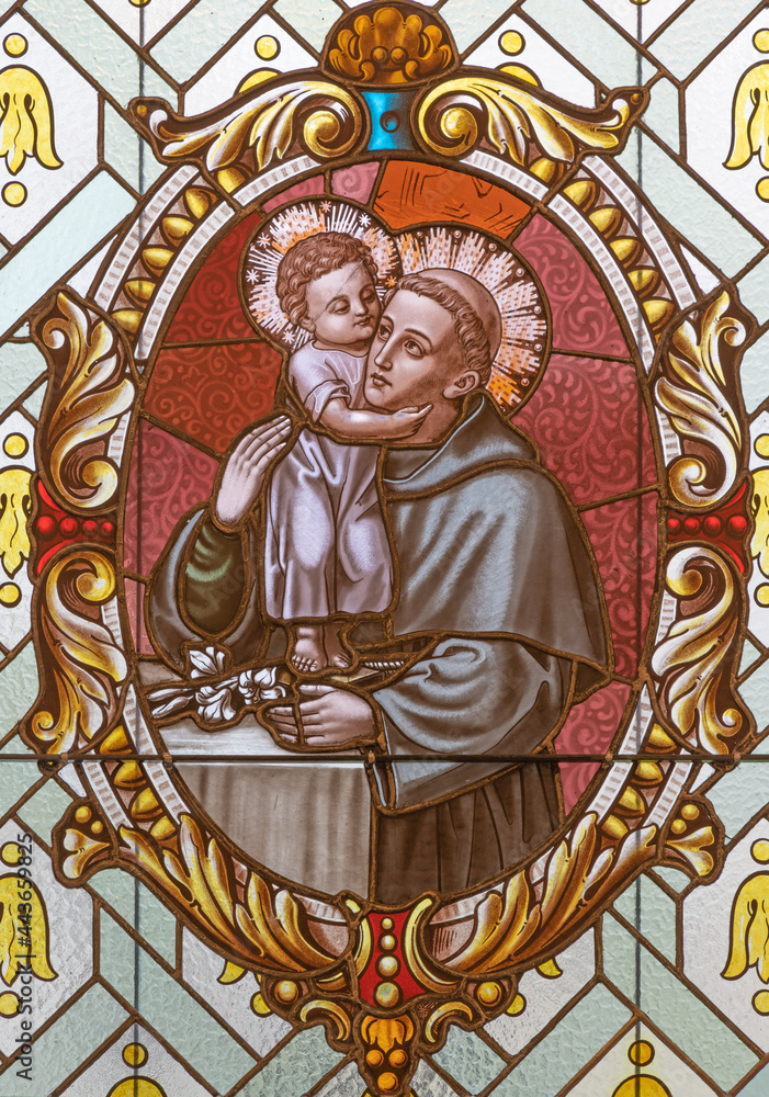 VIENNA, AUSTIRA - JUNI 17, 2021: The  St. Anthony of Padua on the stained glass of church  Alserkirche  by Franz Gotzer from 20. cent.
