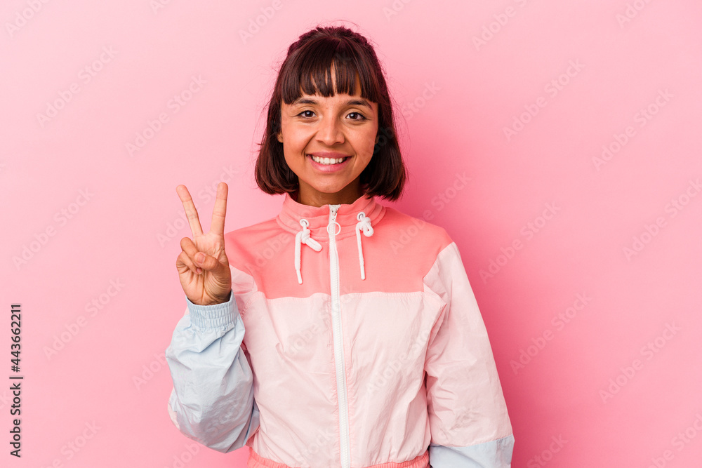 Young mixed race woman isolated on pink background showing victory sign and smiling broadly. Young mixed race woman isolated on pink background showing victory sign and smiling broadly.