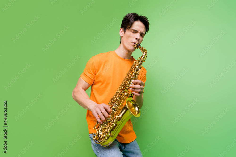 Fototapeta premium Photo of joyful happy young man hold hands play saxophone jazz lover isolated on green color background