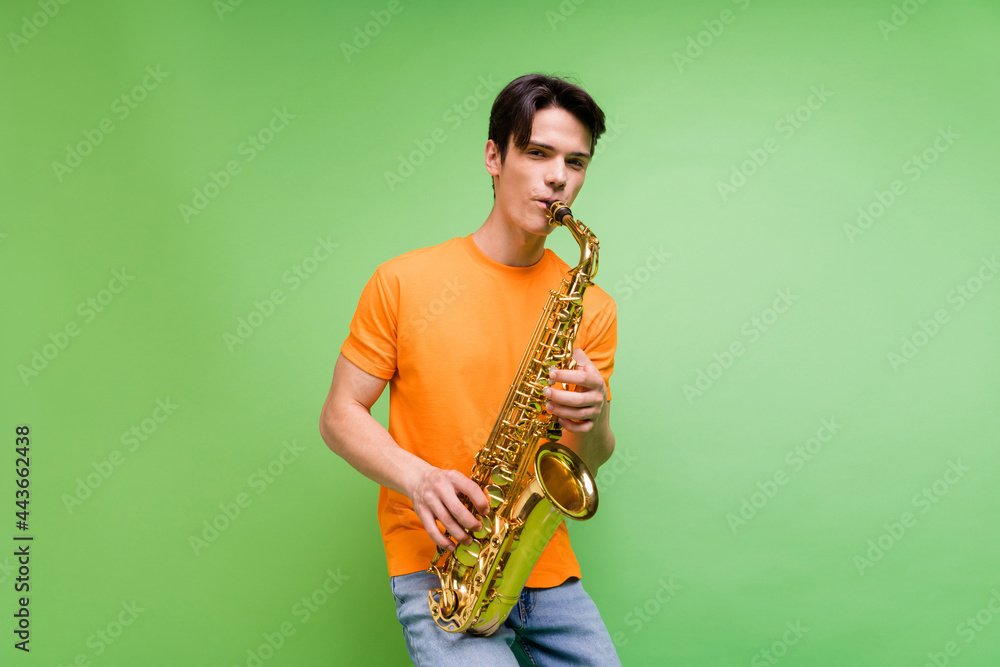 Fototapeta premium Photo of charming positive happy man hold hands saxophone musician isolated on green color background