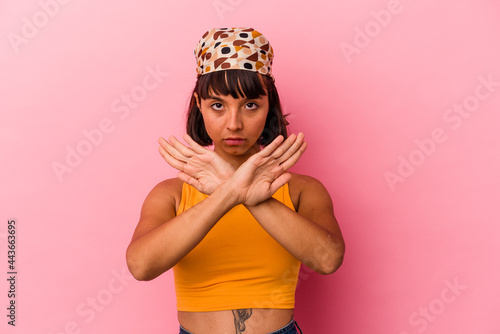 Young mixed race woman isolated on pink background doing a denial gesture